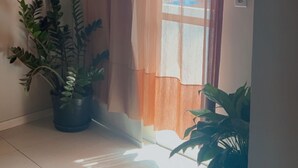 A room with a large window, a potted plant, and a ceiling light. - Studio apartment in Prainha de Muquiçaba, 5 minutes from Praia do Morro, excellent for couples. (Guarapari)