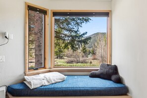 Ein Zimmer mit einem großen Fenster, einer blauen gepolsterten Bank und einem weißen Kissen.