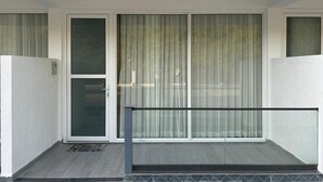 Ein Gebäude mit Balkon, einer Schiebeglastür und einem Metallgeländer.
