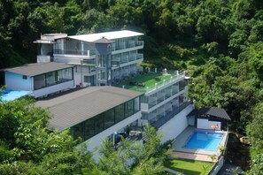 Un edificio moderno de varios pisos con piscina en la azotea y cancha de tenis.