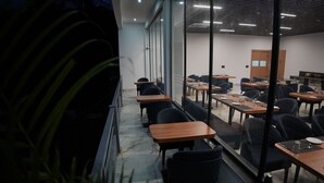 Ein Konferenzraum mit Tischen, Stühlen, großen Fenstern und einer Tür.