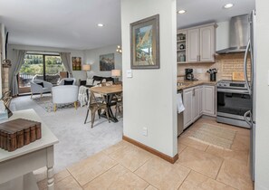 A spacious living area with a dining table, sofas, and a kitchen with modern appliances. - Modern Condo in Avon, Walk to Gondola, SA513 (Avon)