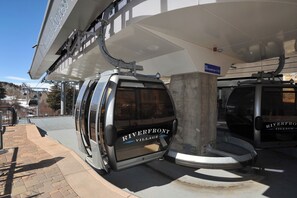 A cable car station with 'Riverfront Village' signage, a covered waiting area, and a clear sky. - Modern Condo in Avon, Walk to Gondola, SA513 (Avon)