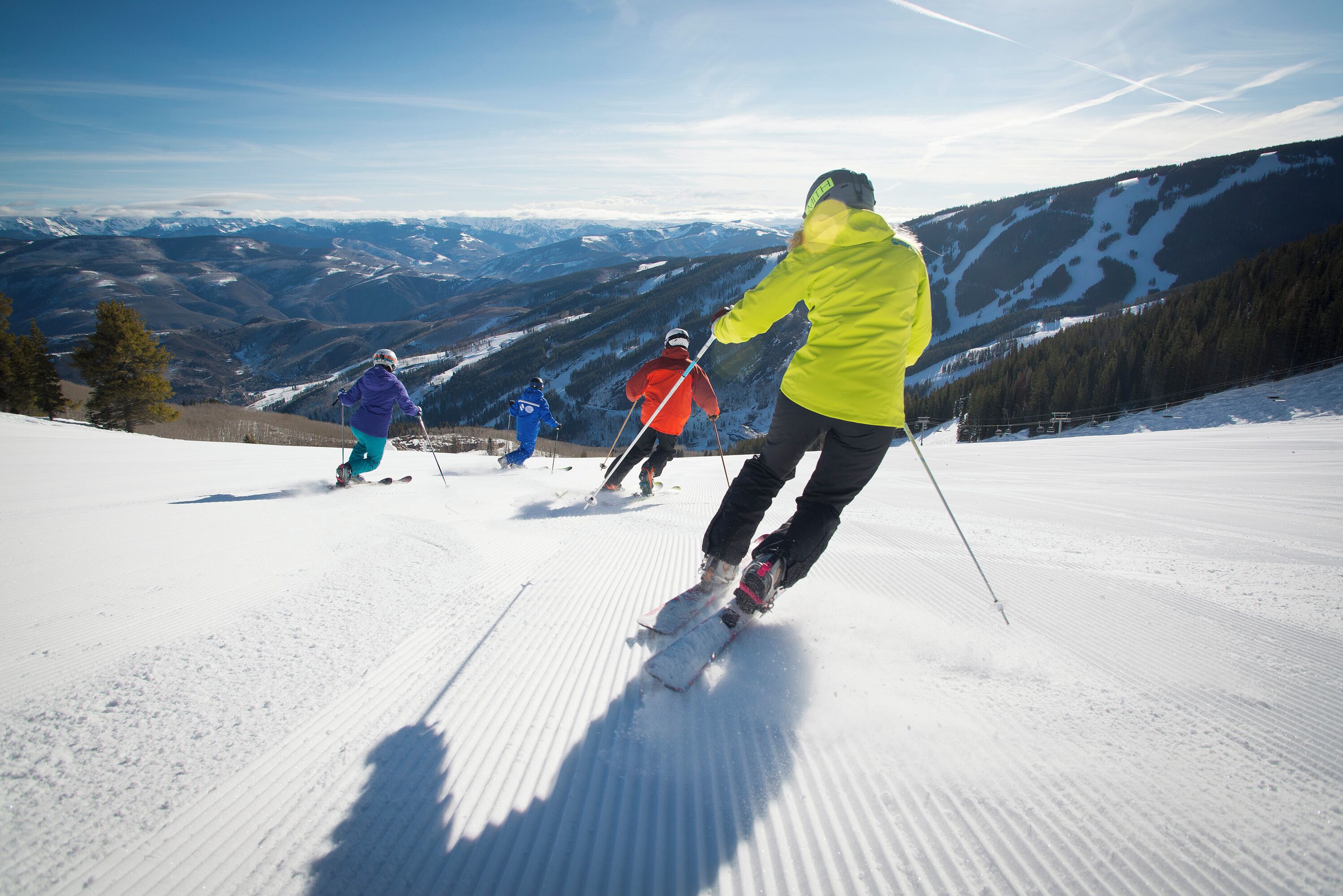 Skiers on a snowy slope with a mountainous backdrop.