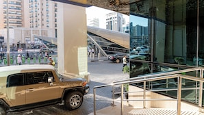 A modern building with a glass facade, a staircase, and a vehicle parked outside.