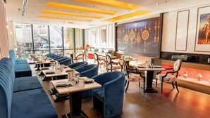 A restaurant with blue upholstered seating, wooden tables, and a large wall with decorative patterns.