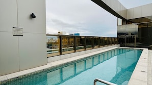 A swimming pool with a tiled deck, metal railings, and a view of buildings in the background. - LK Santo Agostinho 4 (Belo Horizonte)