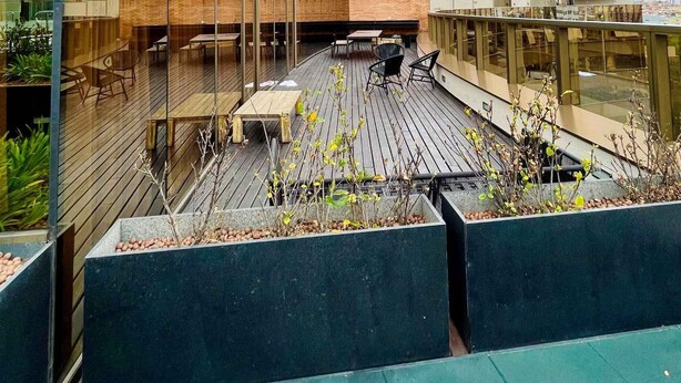 A modern building with a curved glass facade, outdoor seating area with tables and chairs, and a view of the cityscape. - LK Santo Agostinho 4 (Belo Horizonte)