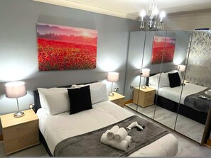 Ein modernes Hotelzimmer mit einem großen Bett, Nachttischlampen, einem Spiegel und einem Gemälde einer Landschaft.