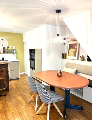 Une cuisine compacte avec un coin repas, un canapé et un escalier.