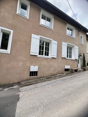 Un bâtiment doté de nombreuses fenêtres, une rue pavée et une petite construction en pierre.