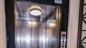 Un ascenseur doté d’un panneau de commande, d’un intérieur métallique et d’une porte avec un panneau en verre.