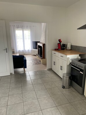 A modern kitchen with a stove, oven, and coffee maker, a TV, and a dining area with a table and chairs.