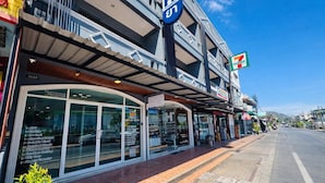 A 7-Eleven convenience store with a pharmacy sign, large windows, and a clear sky. - Henry's House (Wichit)