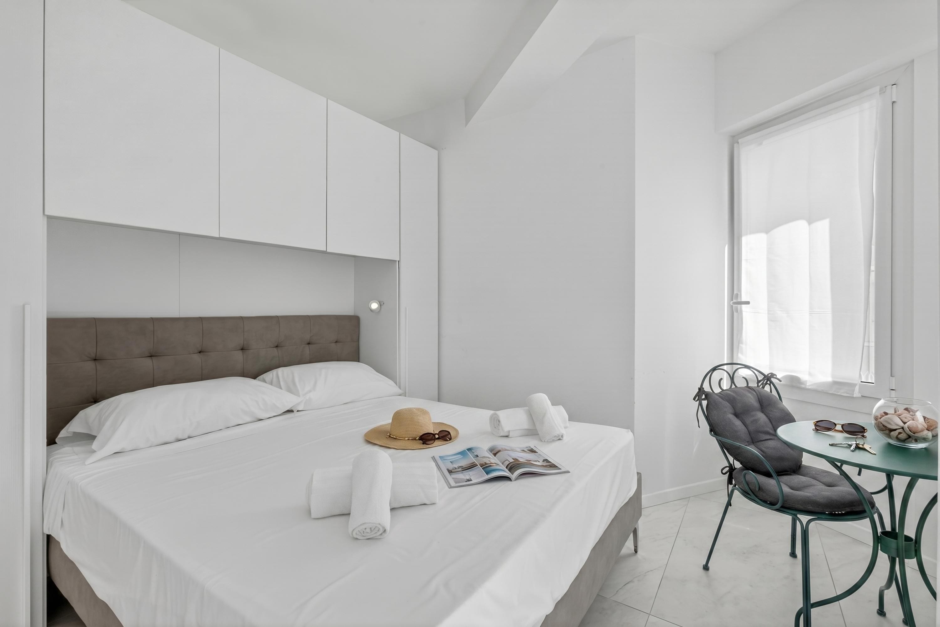 A modern hotel room with a bed, a dining table, and a chair.