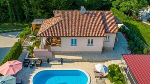 Una casa con piscina, mobiliario de exterior y jardín.