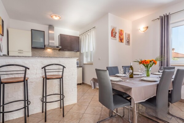 A modern kitchen with a central island, bar stools, and a dining area with a table set for four. - Istrian Villa Stella for 8: Pool & Sauna (Labin)