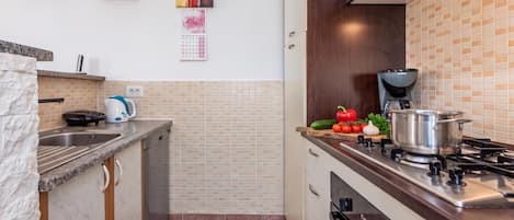 Una cocina moderna con estufa a gas, cafetera y un calendario en la pared.