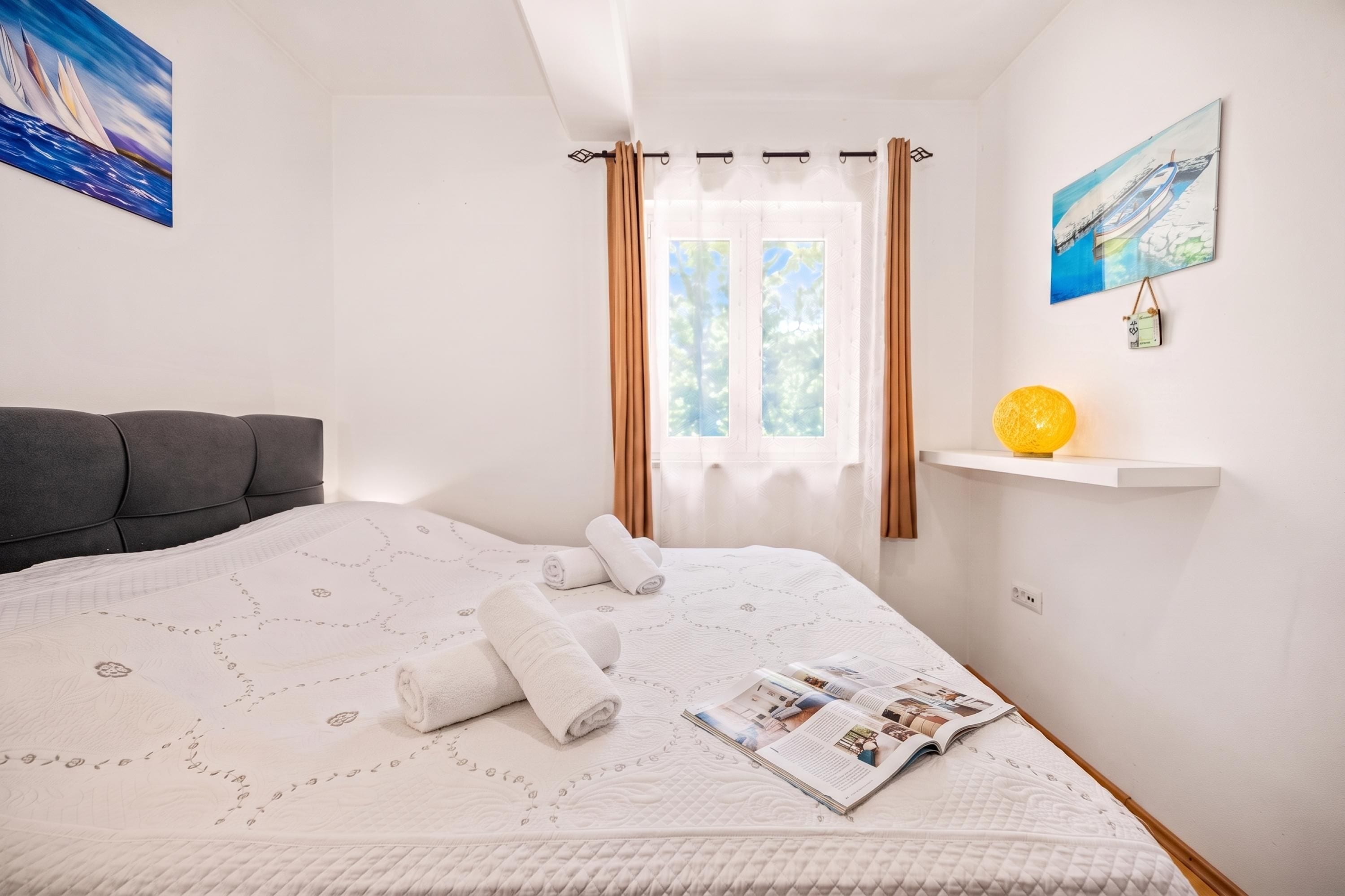 A neatly made bed with a quilt, a magazine, and rolled towels.