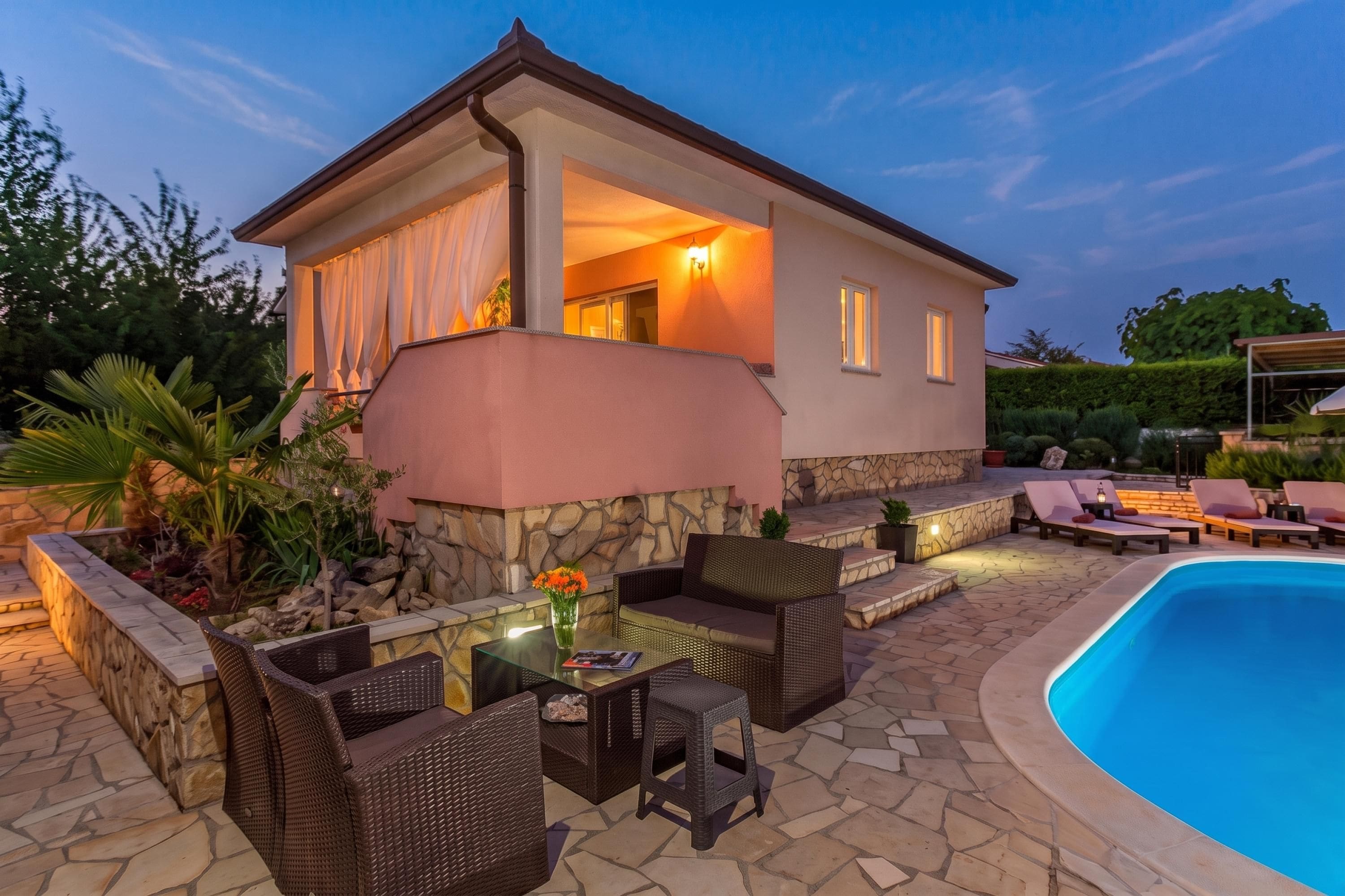 Una casa amb piscina, mobles d'exterior i un camí de pedra.