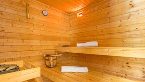 Una sauna de madera con bancos, un termómetro y un balde.