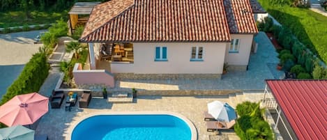 A house with a swimming pool, outdoor furniture, and a garden.