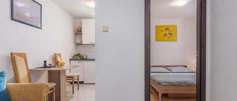 A room with a bed, a desk, a chair, a clock, and a painting on the wall.