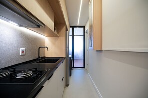 A modern kitchen with a gas stove, stainless steel appliances, and a view of the adjacent living area. - Ipanema One-bedroom Near Ipanema Beach (Rio de Janeiro)