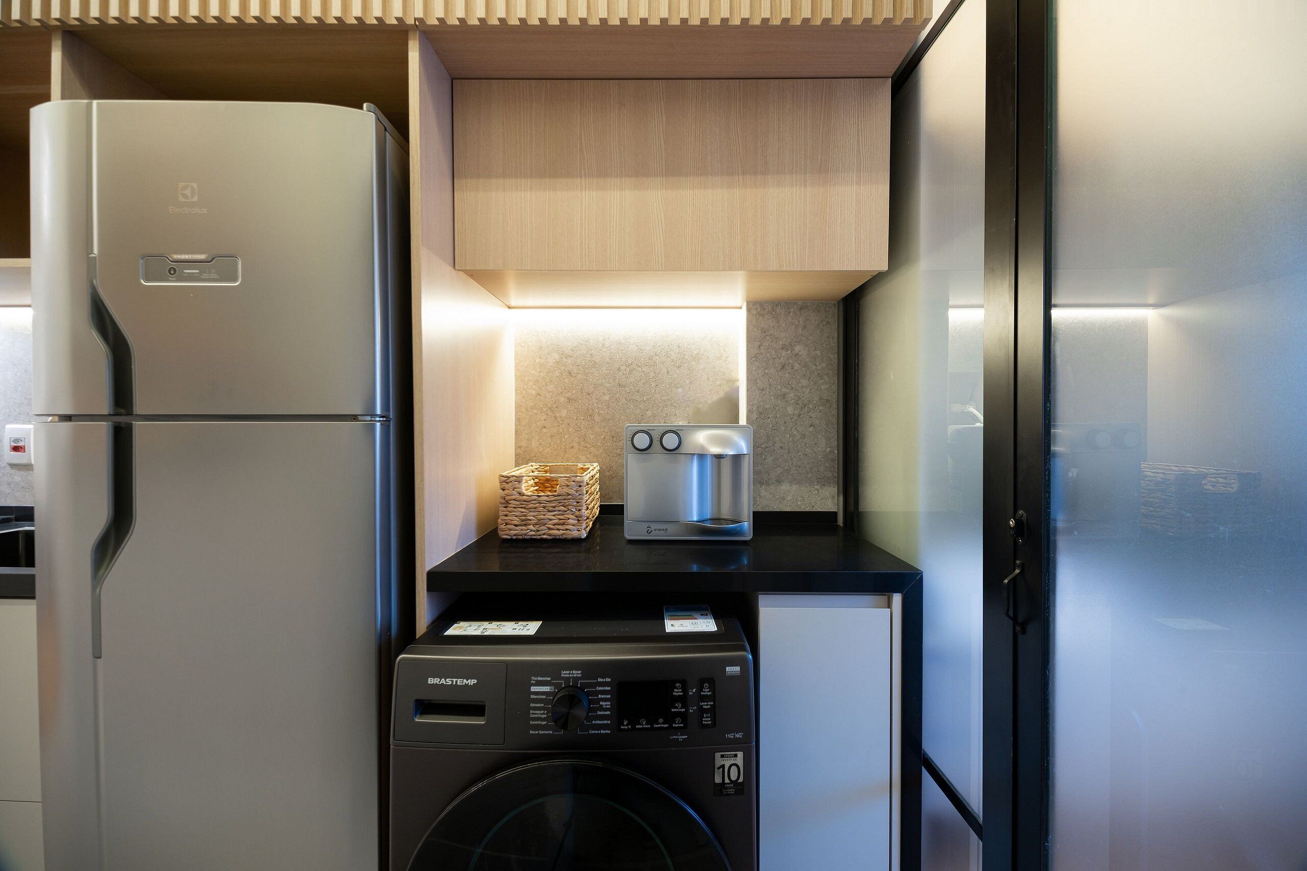 A compact kitchen with a refrigerator, washing machine, and a toaster.