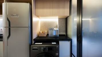 A compact kitchen with a refrigerator, washing machine, and a toaster.