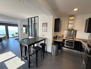 A modern kitchen with a view of the sea, a dining area with chairs, and a large window. - Agi Joan Margarit 24 Casa for rent in Roses Girona. (Roses)
