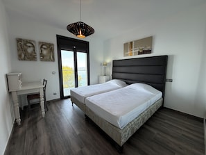 A modern bedroom with a large bed, a desk, and a view through the door. - Agi Joan Margarit 24 Casa for rent in Roses Girona. (Roses)