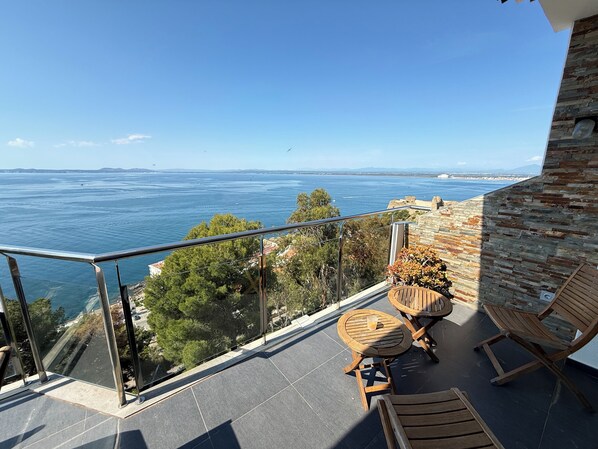 A balcony with a view of the sea, wooden furniture, and a stone wall. - Agi Joan Margarit 24 Casa for rent in Roses Girona. (Roses)