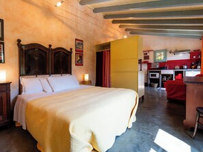 Ein Schlafzimmer mit einem großen Bett, einem Holzkopfende, einem Nachttisch mit Lampe und einem weiteren kleinen Nachttisch ebenfalls mit Lampe.