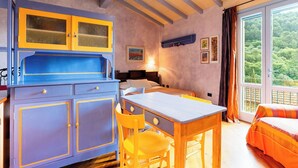Een kamer met een bed, een bureau en een stoel. Er is een raam met uitzicht op bomen.