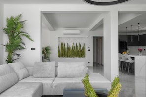 Ein modernes Wohnzimmer mit einer Couch, einer großen Kübelpflanze und einem Wandbild.