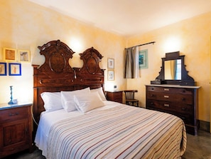 Une chambre à coucher avec un grand lit, une tête de lit en bois, une commode, une chaise et un miroir.