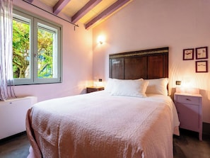 Ein Schlafzimmer mit einem Bett, Nachttischen, einem Fenster und einer Wandleuchte.