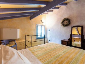 Ein Schlafzimmer mit Bett, Schreibtisch mit Lampe, Spiegel und einem fenster mit Vorhängen.