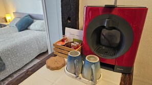 Une chambre d’hôtel avec un lit, une machine à café, un plateau de collations et deux tasses sur la table.
