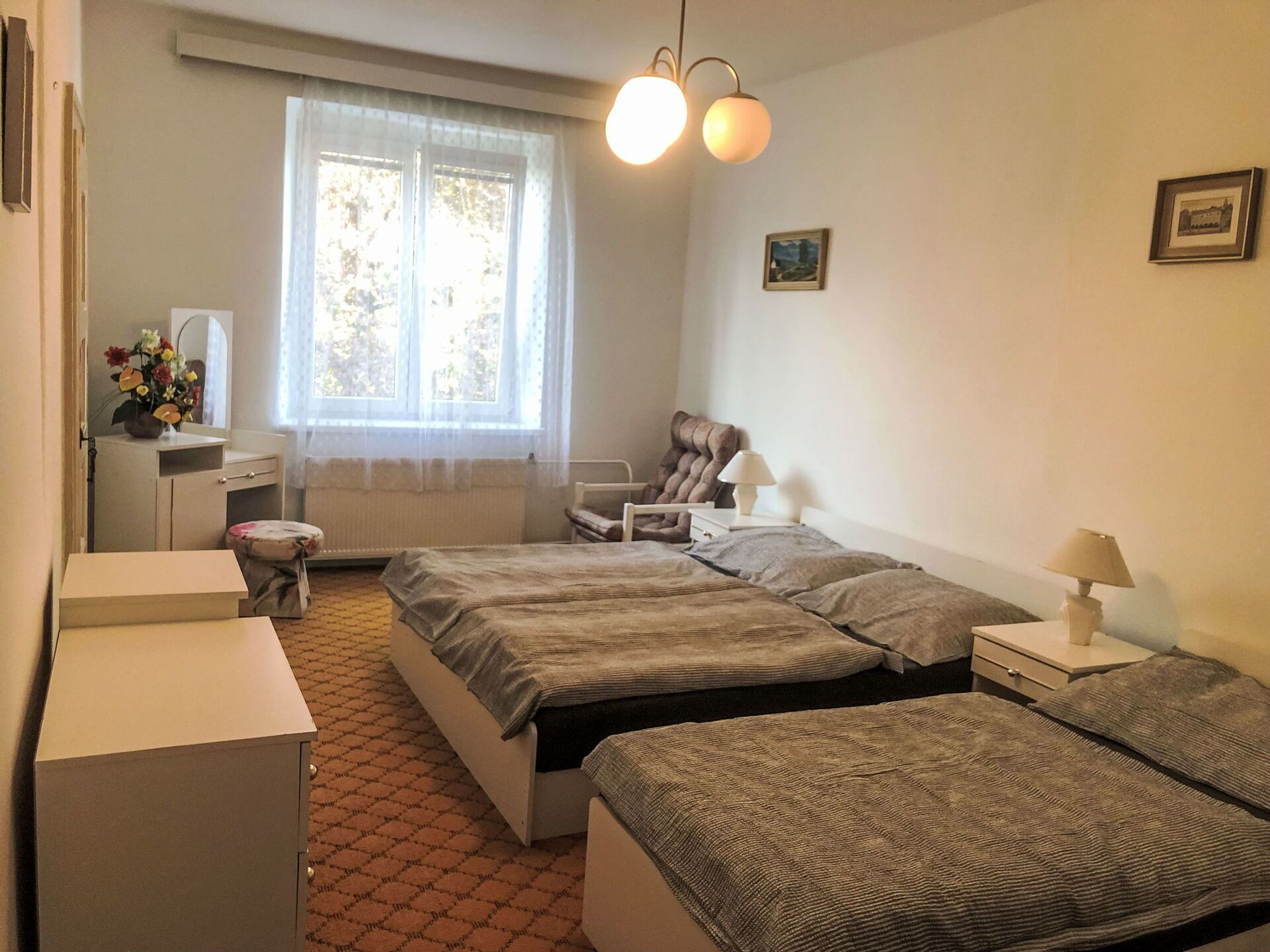 A bedroom with two beds, a desk, a chair, and a window with curtains.