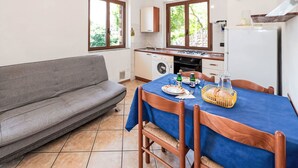 Cozinha compacta com área de refeições, um sofá e uma mesa posta para dois.