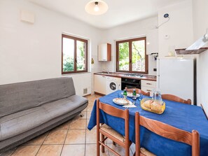 Una cucina compatta con zona pranzo, un divano e un tavolo apparecchiato per due.