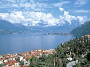 A coastal town with red-roofed buildings, a large body of water, and mountains in the background. - Cosy apartment for 4 guests with WIFI, TV, balcony and pets allowed (Bellano)