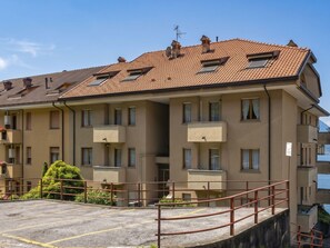 Un edificio residencial de varios pisos con balcones, un estacionamiento y vista al mar.