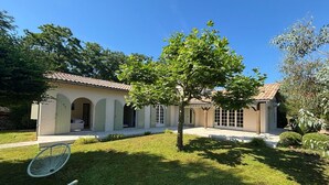 Uma casa com telhado de telhas, varanda coberta e gramado bem cuidado.