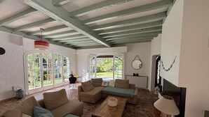 Uma sala de estar ampla com teto alto, janelas grandes e lareira.