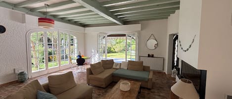 Uma sala de estar ampla com teto alto, janelas grandes e lareira.