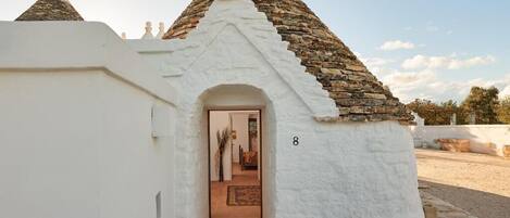 A traditional stone-roofed building with a white exterior and a door leading to an interior space.