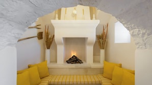 Une pièce chaleureuse avec une cheminée, des coussins jaunes et un manteau de cheminée blanc.